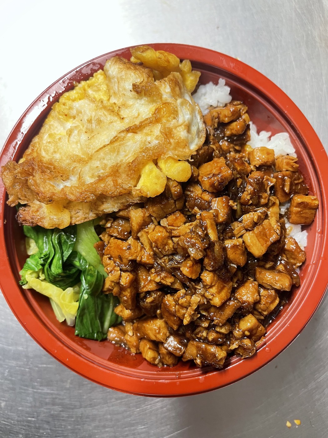A Top Chef rice box of soy-glazed diced chicken over rice with a fried egg and pak choi